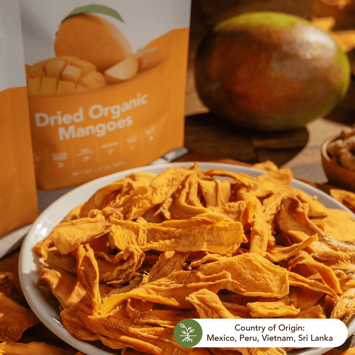 Plate of dried organic mango slices beside the pouch and a fresh mango